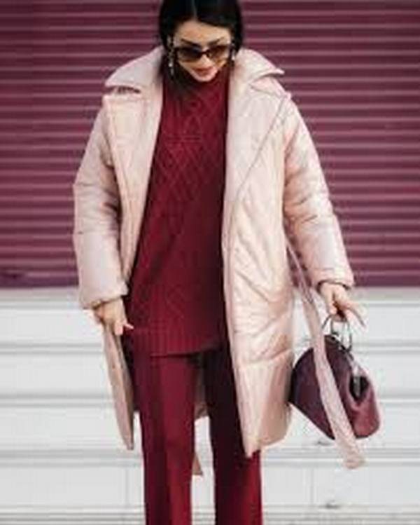 Стильное дополнение к повседневному луку с удлиненным розовым пуховиком – небольшая сумочка в одной цветовой гамме со свитером и брюками