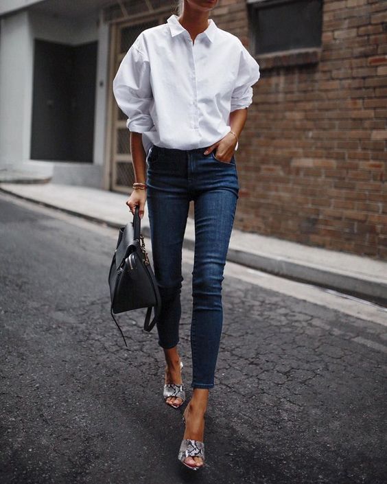 Белая свободная рубашка, заправленная в темно-синие джинсы скинни и босоножки на платформе с открытой пяткой и носком анималистического принта. 