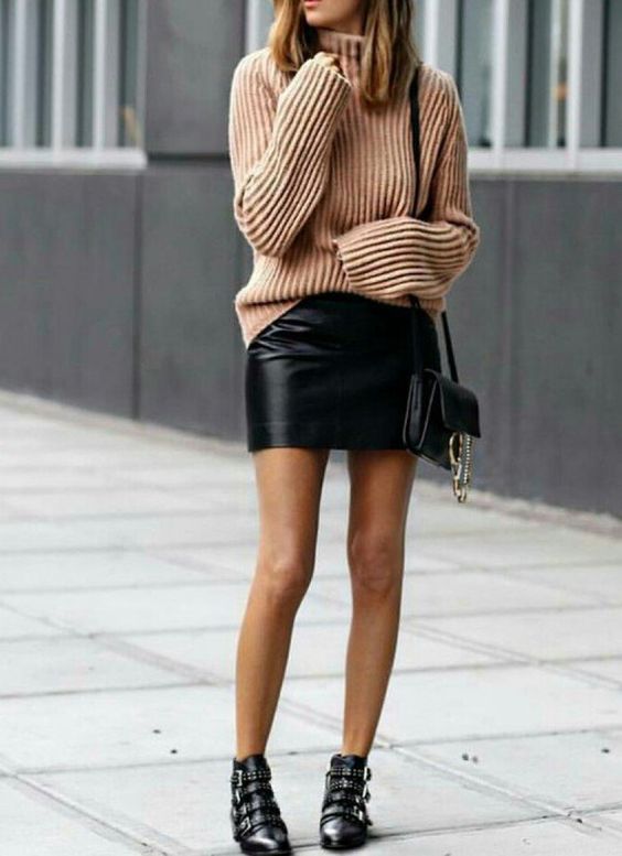 Бежевый свитер оверсайз в сочетании с кожаной прямой юбкой-мини, черными ботинками с ремешками, кожаной сумкой.