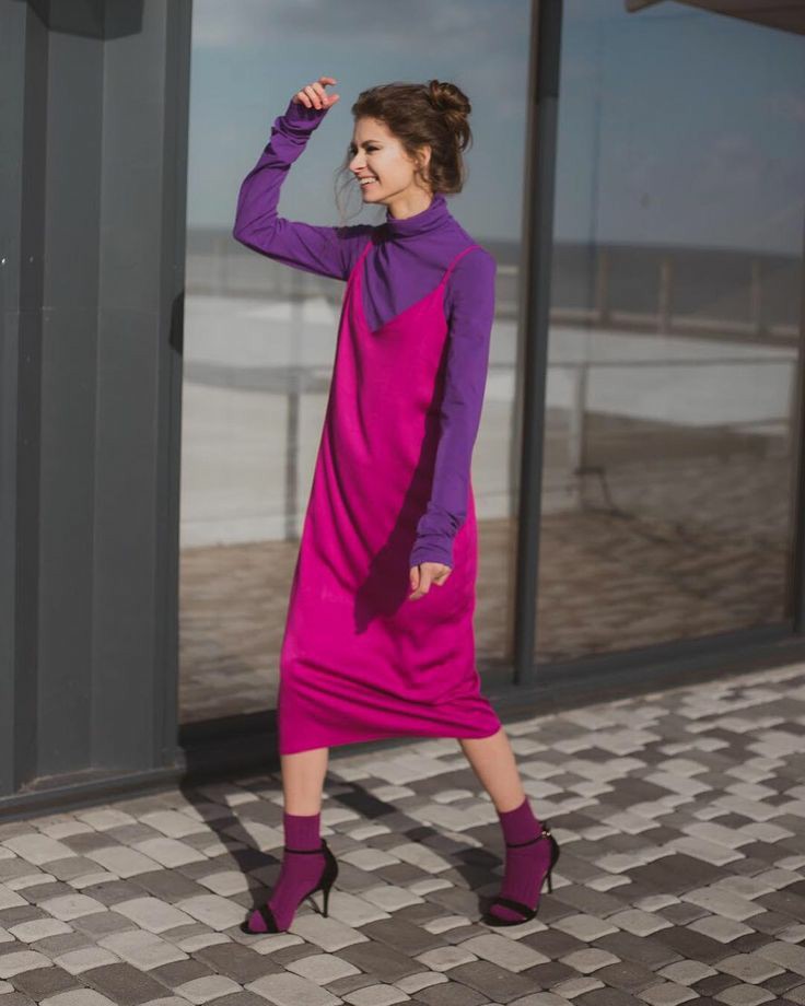 На девушке фиолетовая водолазка с воротом, шелковое яркое розовое платье свободного кроя длины миди, темно-фиолетовые носки, черные босоножки на тонком каблуке и с открытым носом.