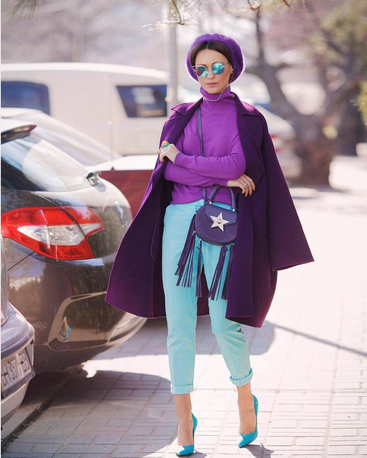 На девушке сиреневая водолазка с высоким воротом, мятные укороченные брюки со средней талией, голубые лодочки на каблуке и с заостренным носом, темно-фиолетовое пальто прямого кроя, фиолетовое кепи, поясная сумка с бахромой.