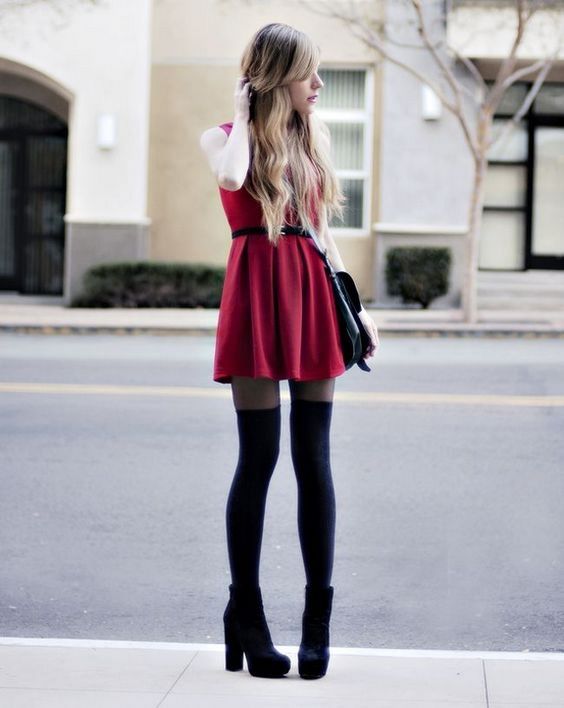 На девушке красное короткое платье с пышной юбкой, черные гольфы и ботинки на высоком каблуке.